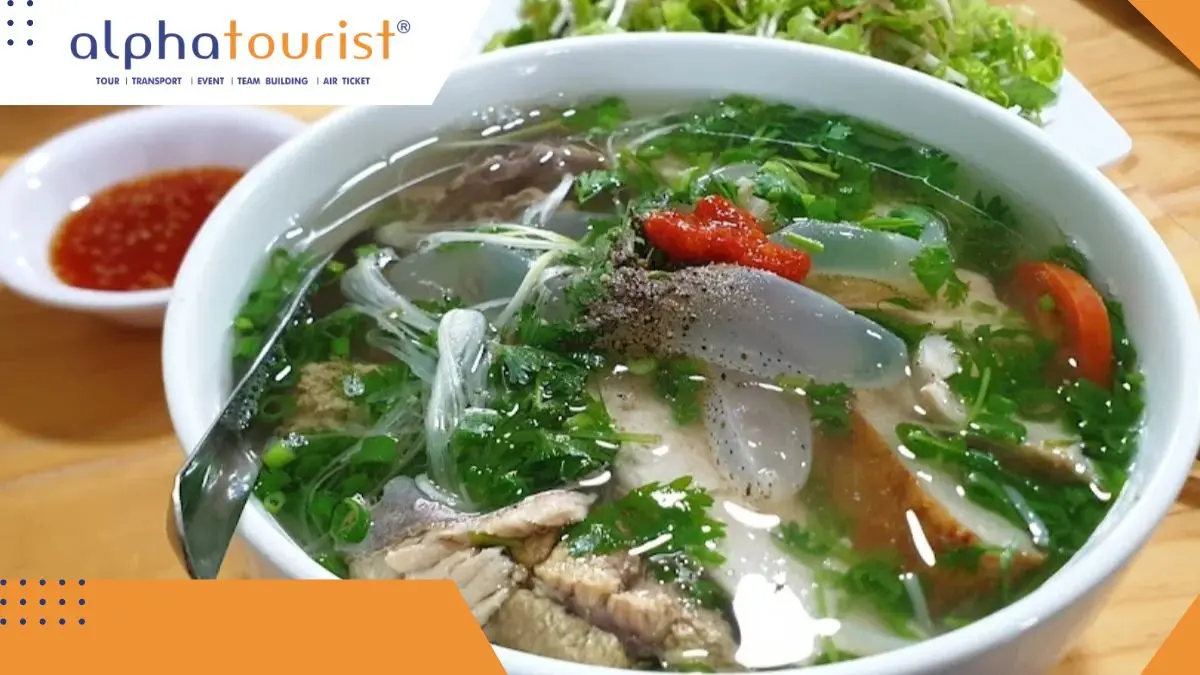 Ảnh chụp từ trên xuống một tô bún sứa Nha Trang, nổi bật với những miếng sứa trắng trong, chả cá, cà chua và rau thơm xanh mướt trong nước dùng