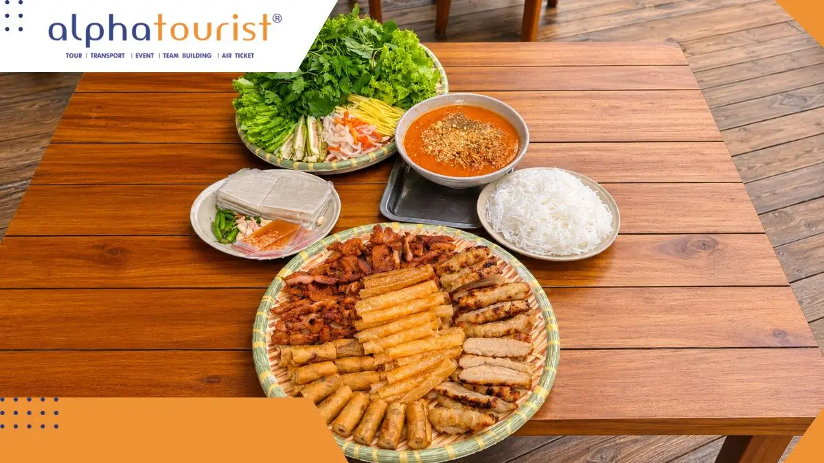 Một mẹt tre lớn bày đầy đủ nem nướng Ninh Hòa, bánh tráng chiên giòn, các loại rau sống tươi xanh và một chén nước chấm màu cam đặc sệt ở trung tâm