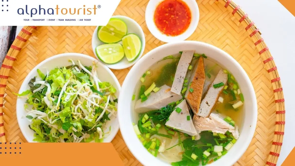 Cận cảnh một tô bún chả cá Nha Trang với những miếng chả cá chiên vàng và chả cá hấp trắng ngần, bên trên là hành lá và rau thơm, khói bốc lên từ nước dùng trong